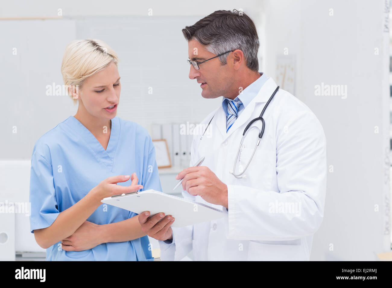 Arzt und Krankenschwester diskutieren über Noten in Klinik Stockfoto