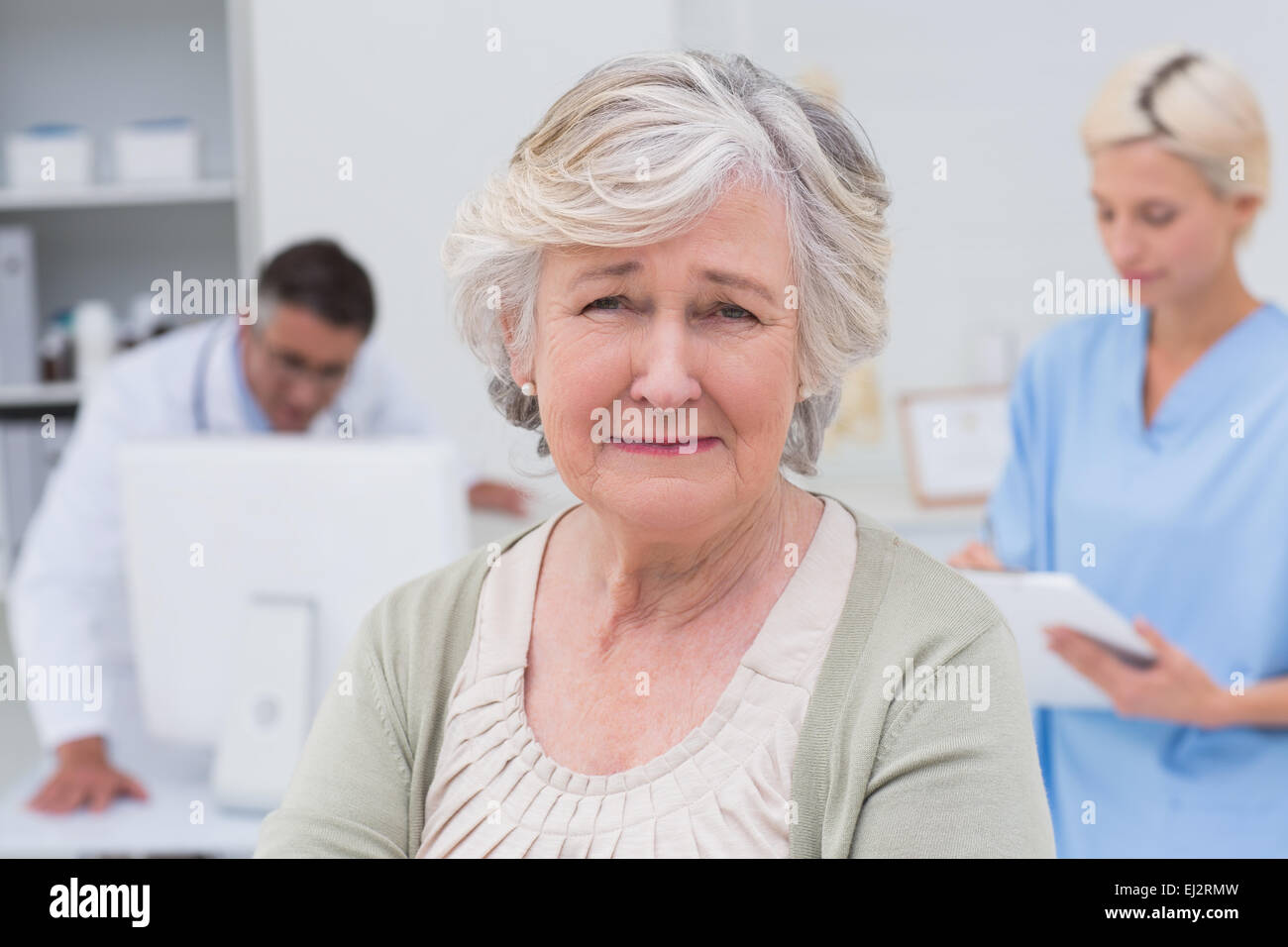 Unglückliche Patient mit Arzt und Krankenschwester arbeitet im Hintergrund Stockfoto