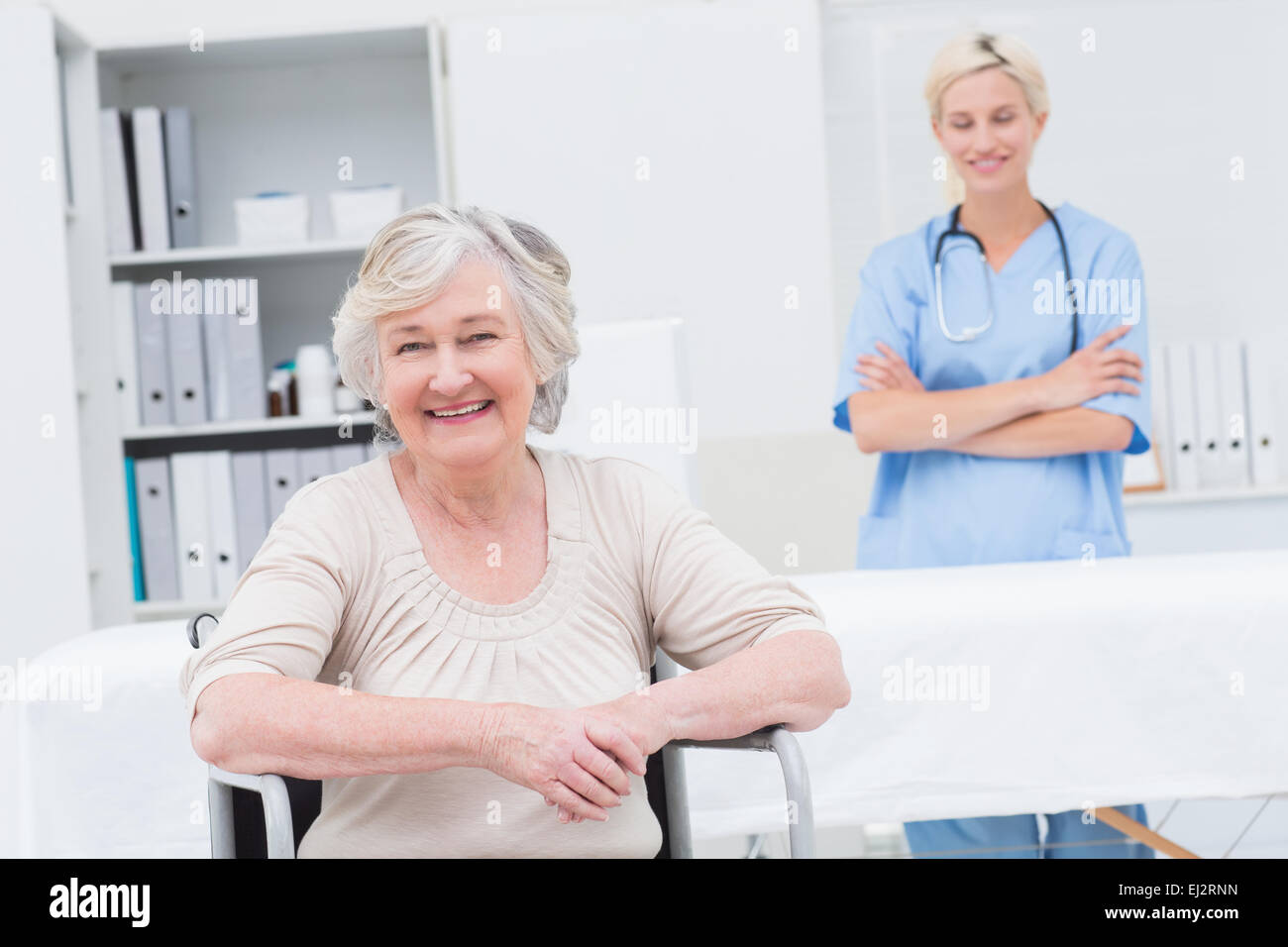 Ältere Patienten sitzen im Rollstuhl und Krankenschwester stehen im Hintergrund Stockfoto