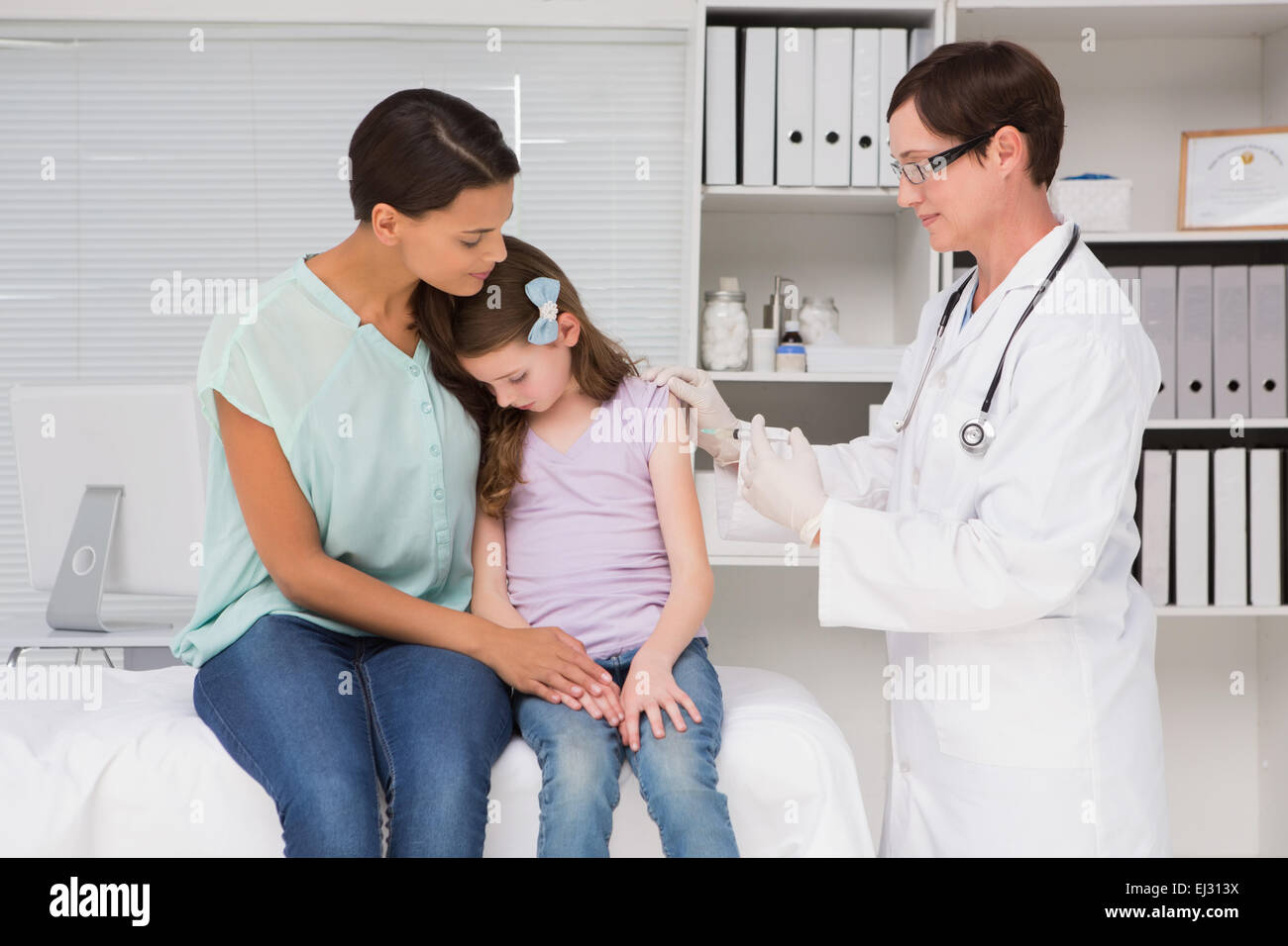 Arzt Injektion in ein kleines Mädchen mit ihrer Mutter zu tun Stockfoto