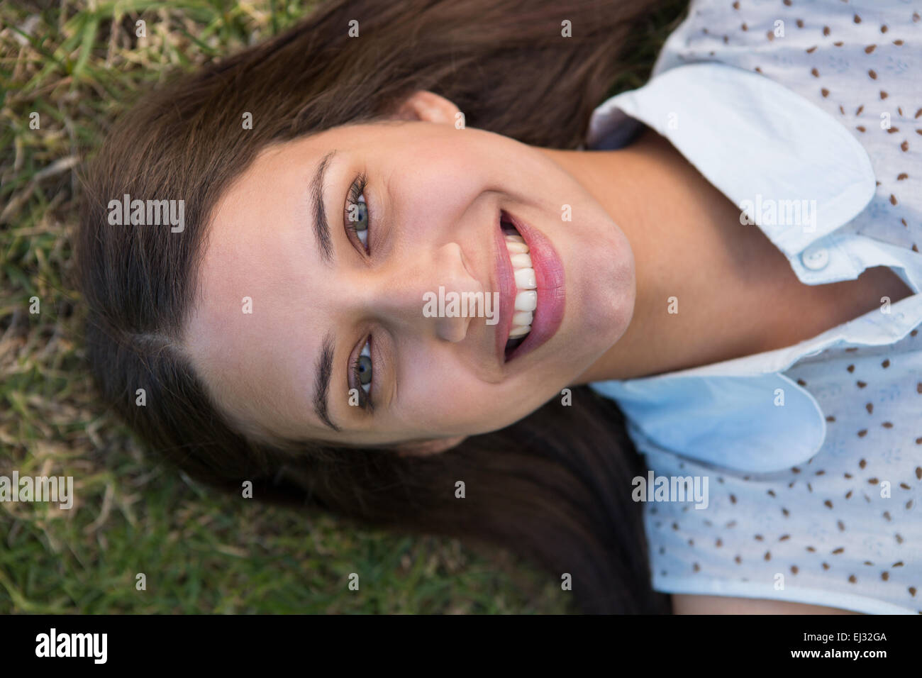 Hübsche Brünette lächelnd in die Kamera auf dem Rasen Stockfoto