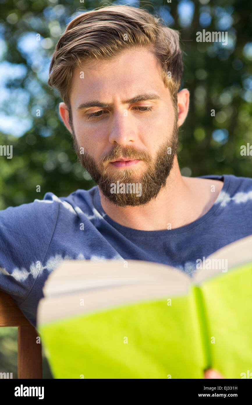 Junger Mann auf der Parkbank lesen Stockfoto