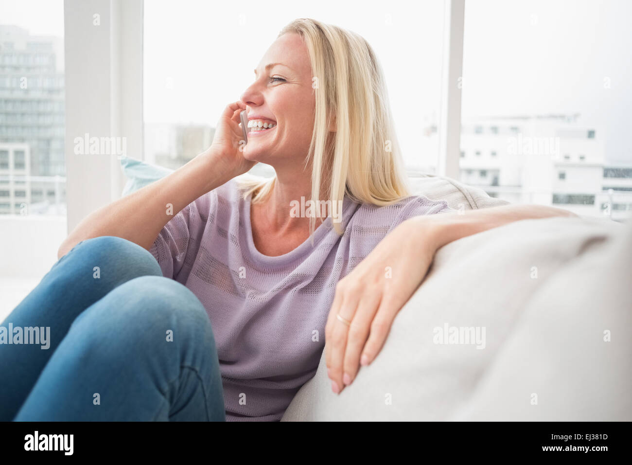 Lächelnde Frau telefonieren mit Handy auf sofa Stockfoto