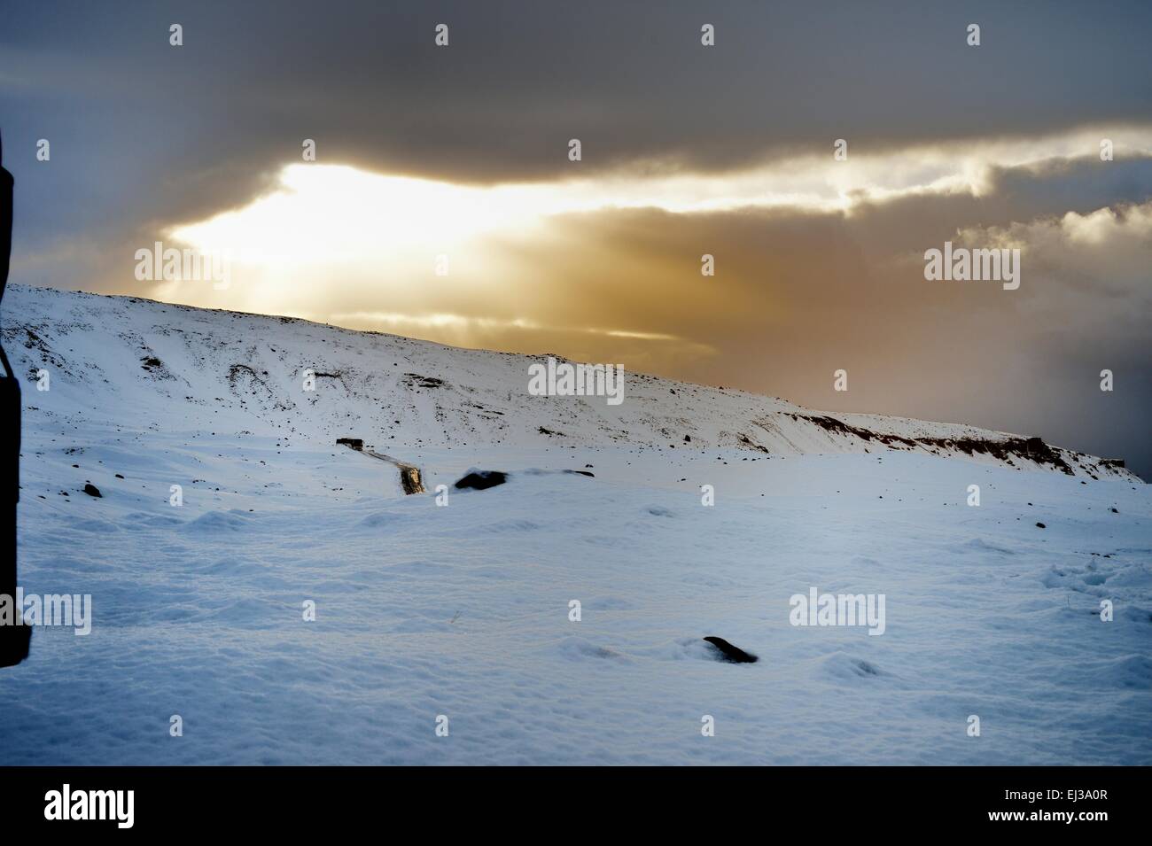 Ein Tourbus fährt auf einer vereisten Straße durch Schneeberge im Winter, Island Stockfoto