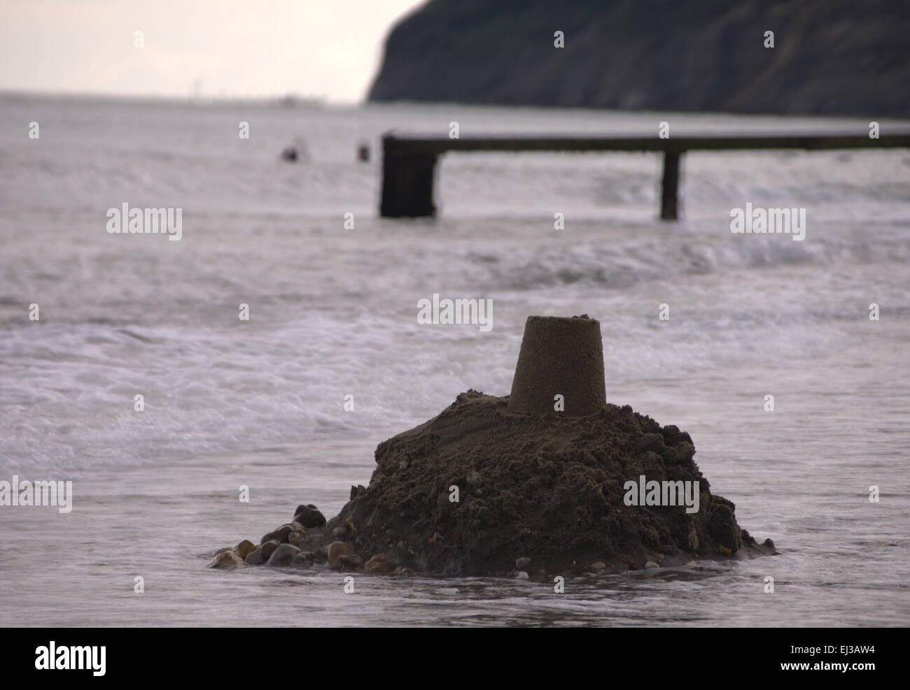 Eine Sandburg zerfällt in das Meer Stockfoto