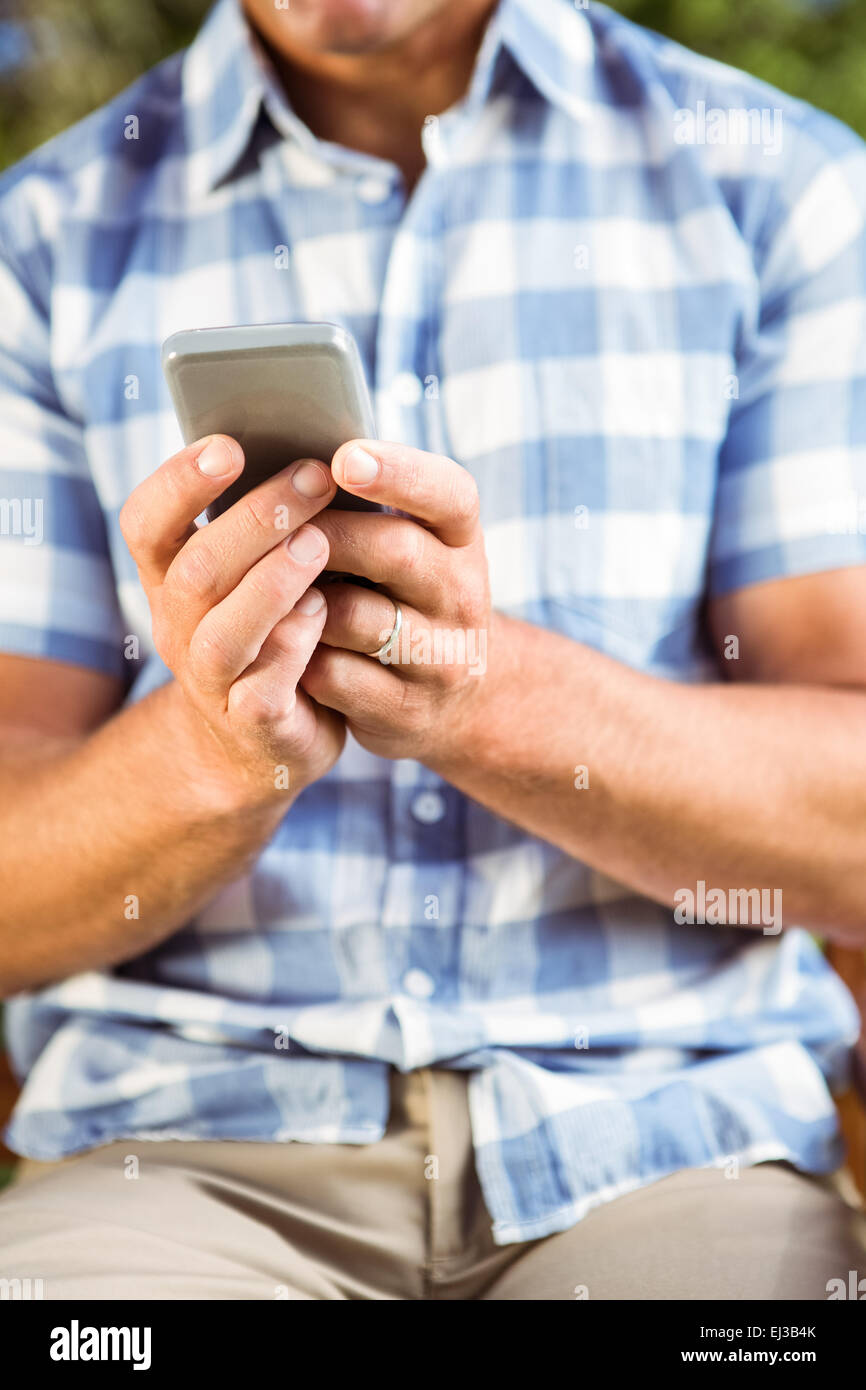 Mann sitzt auf der Parkbank mit Telefon Stockfoto