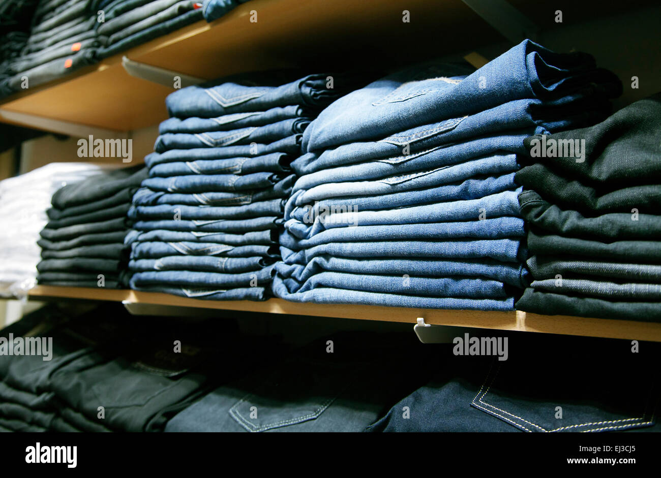 Viele gefaltete Jeans in Regalen in einem Geschäft Stockfoto