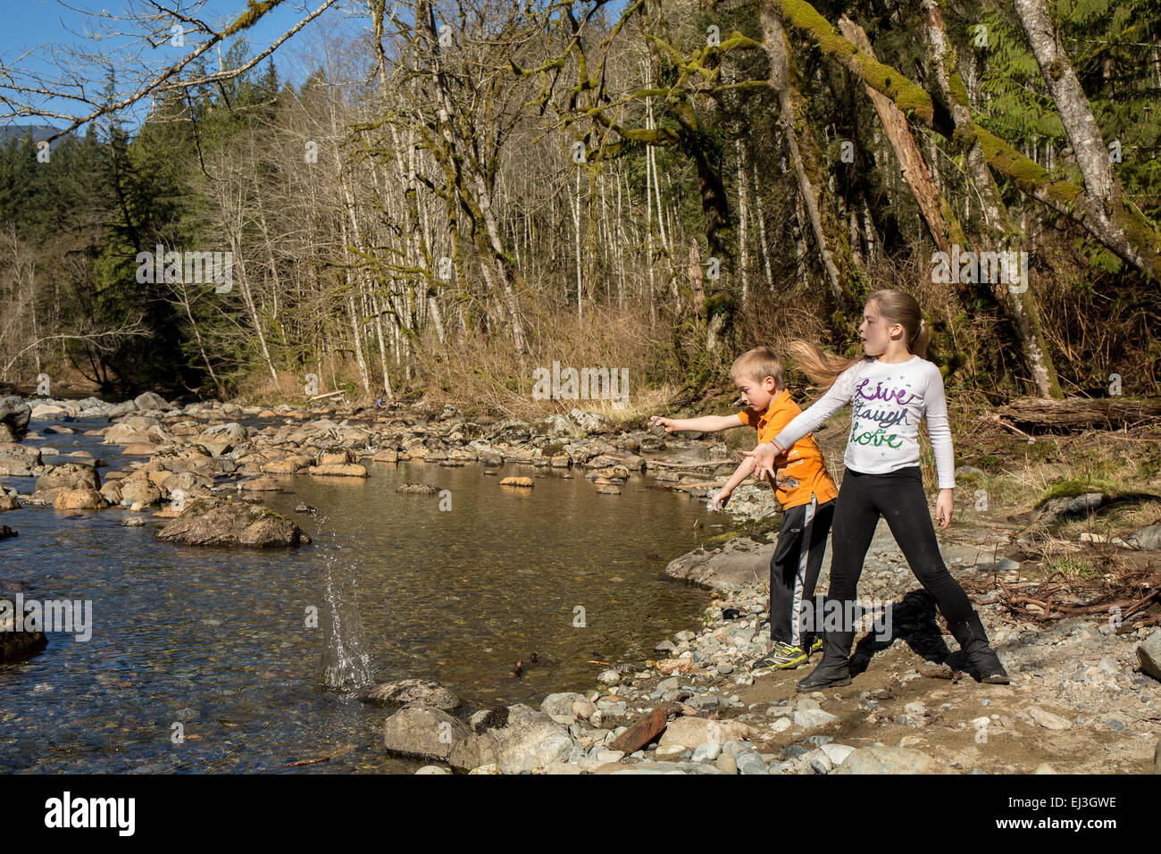 Neun Jahre altes Mädchen und sieben Jahre alten Jungen werfen von Steinen in den Snoqualmie River in der Nähe von North Bend, Washington, USA Stockfoto