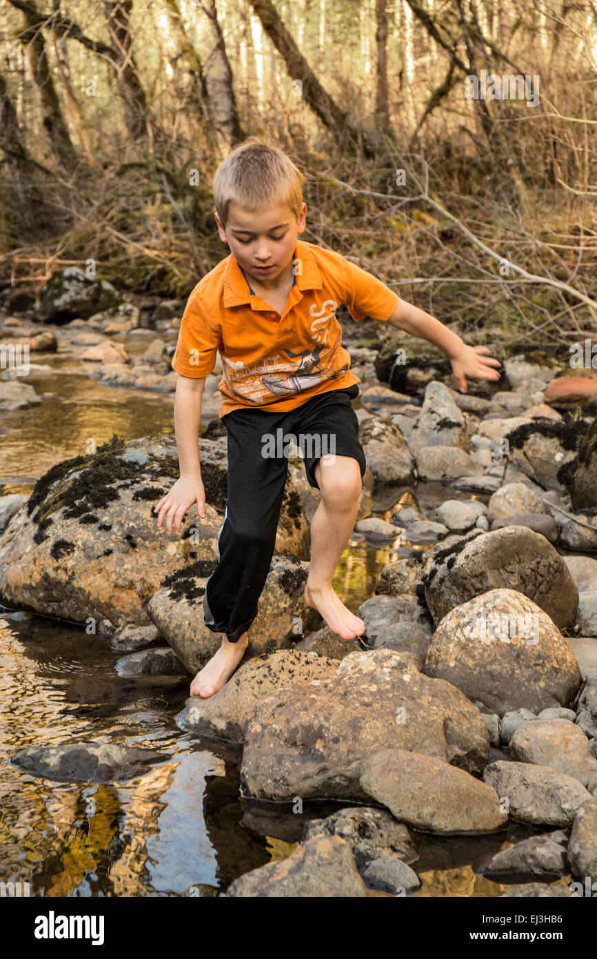 Sieben Jahre alten barfuß junge Klettern auf Felsen in Snoqualmie River in der Nähe von North Bend, Washington, USA Stockfoto