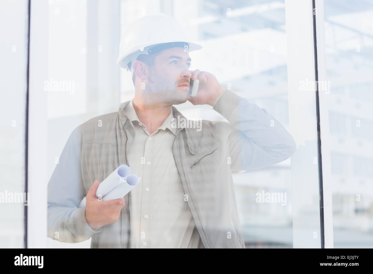 Architekt mit Blaupausen mit Handy im Büro Stockfoto