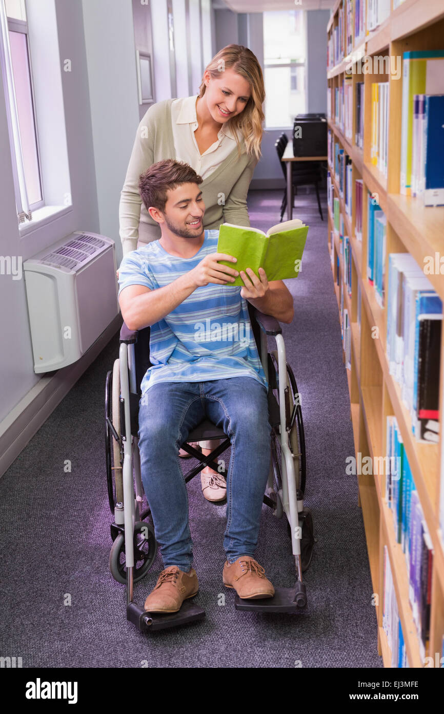 Lächelnd behinderte Schüler mit Klassenkameraden in Bibliothek Stockfoto