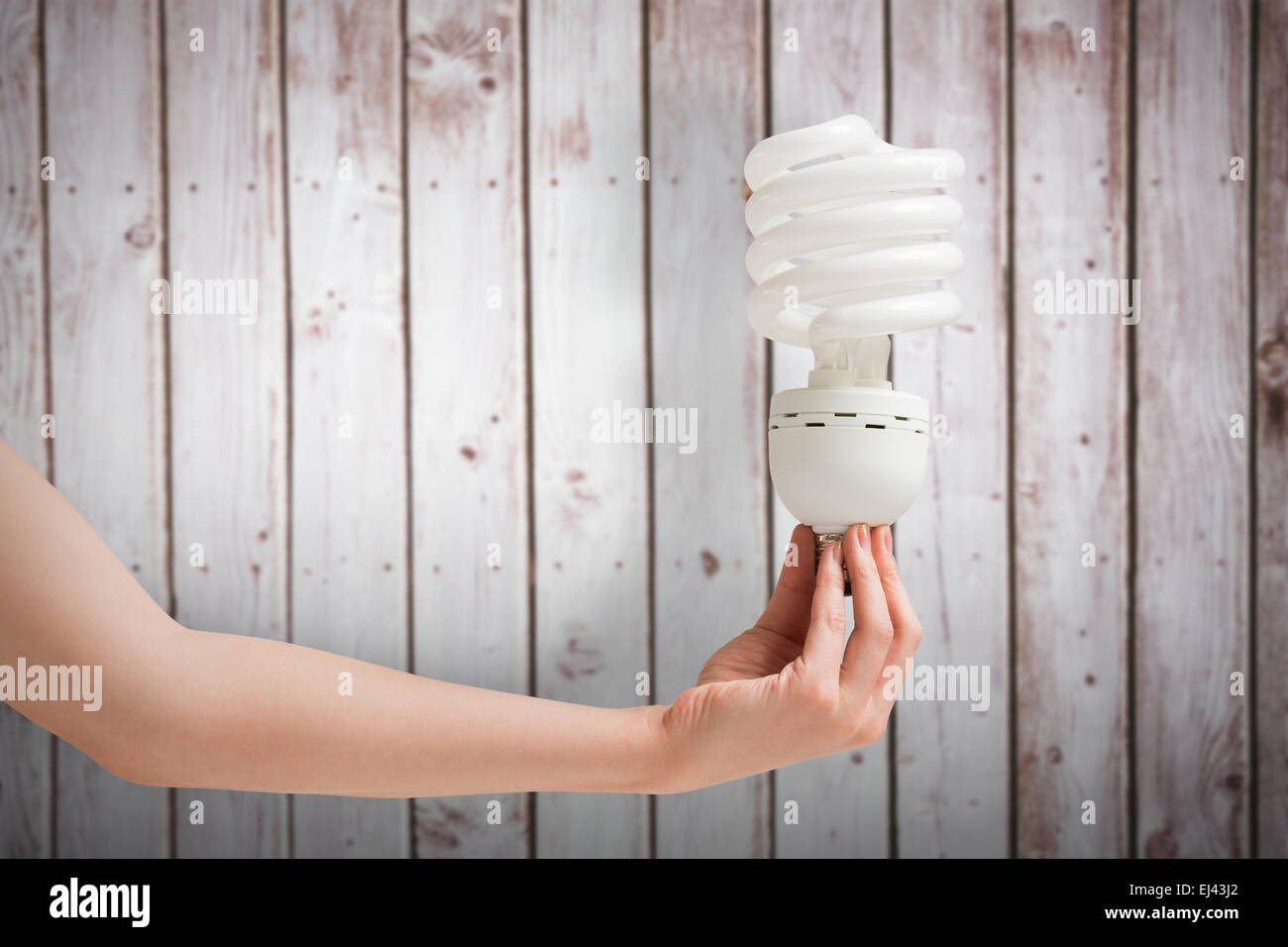 Zusammengesetztes Bild von Hand, die Energie effiziente Glühbirne Stockfoto