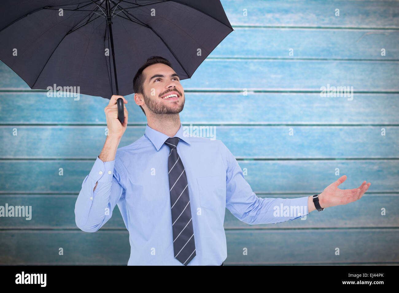 Zusammengesetztes Bild des glücklichen Geschäftsmann mit einem schwarzen Schirm schützt Stockfoto
