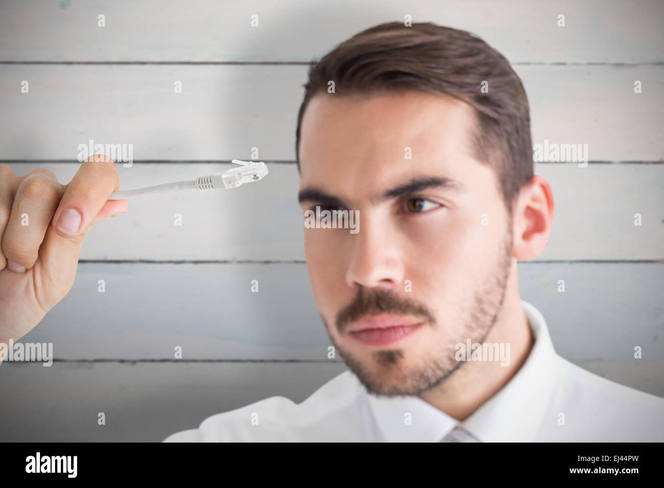Zusammengesetztes Bild des fokussierten Geschäftsmann hält weißes Kabel Stockfoto