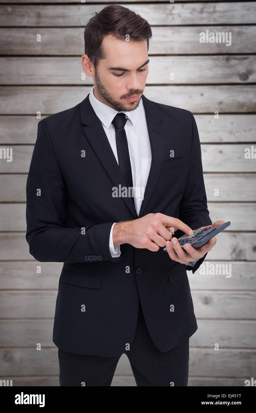 Zusammengesetztes Bild des konzentrierten Geschäftsmann im Anzug mit Taschenrechner Stockfoto