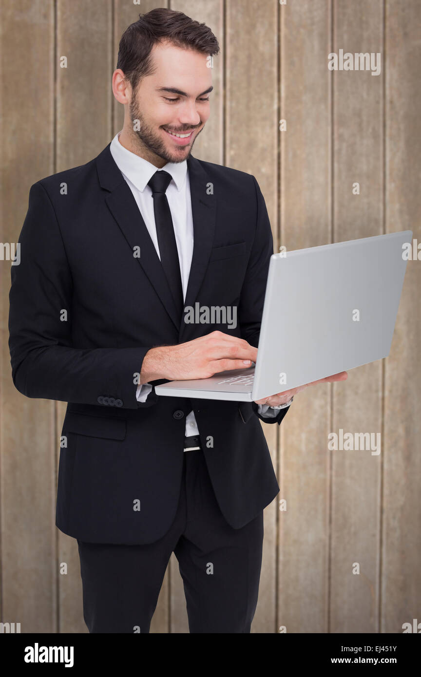 Zusammengesetztes Bild des lächelnden Geschäftsmann stehend und mit laptop Stockfoto