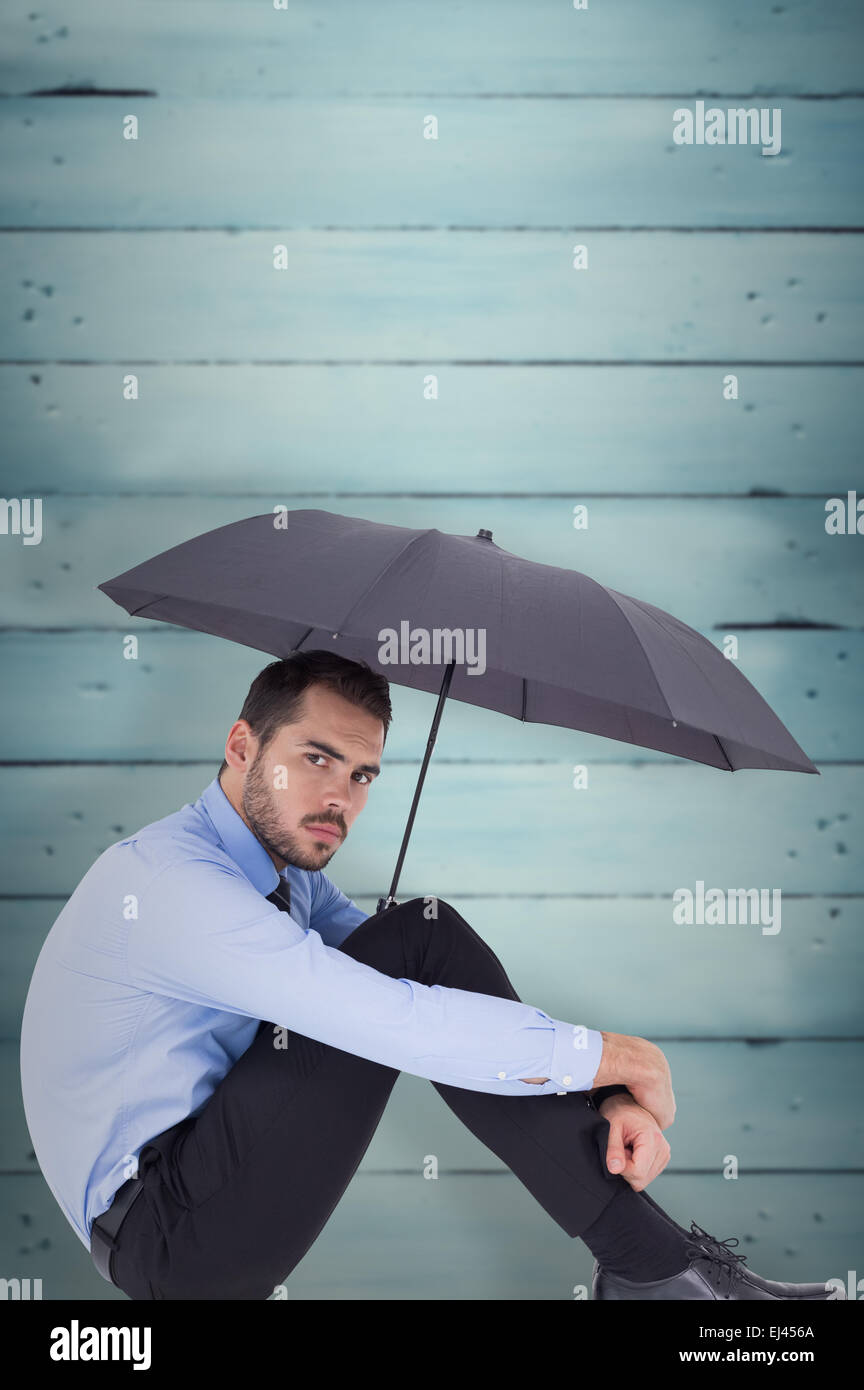 Zusammengesetztes Bild von Ernst Kaufmann hält Regenschirm auf dem Boden sitzend Stockfoto