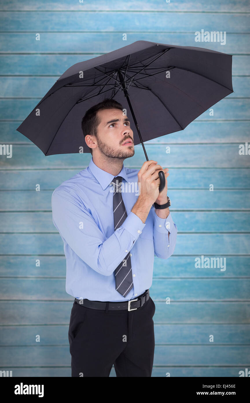 Zusammengesetztes Bild des ängstlichen Geschäftsmann bergende mit Regenschirm Stockfoto