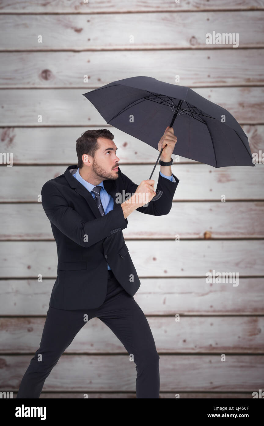 Zusammengesetztes Bild der Geschäftsmann hält Regenschirm um sich zu schützen Stockfoto