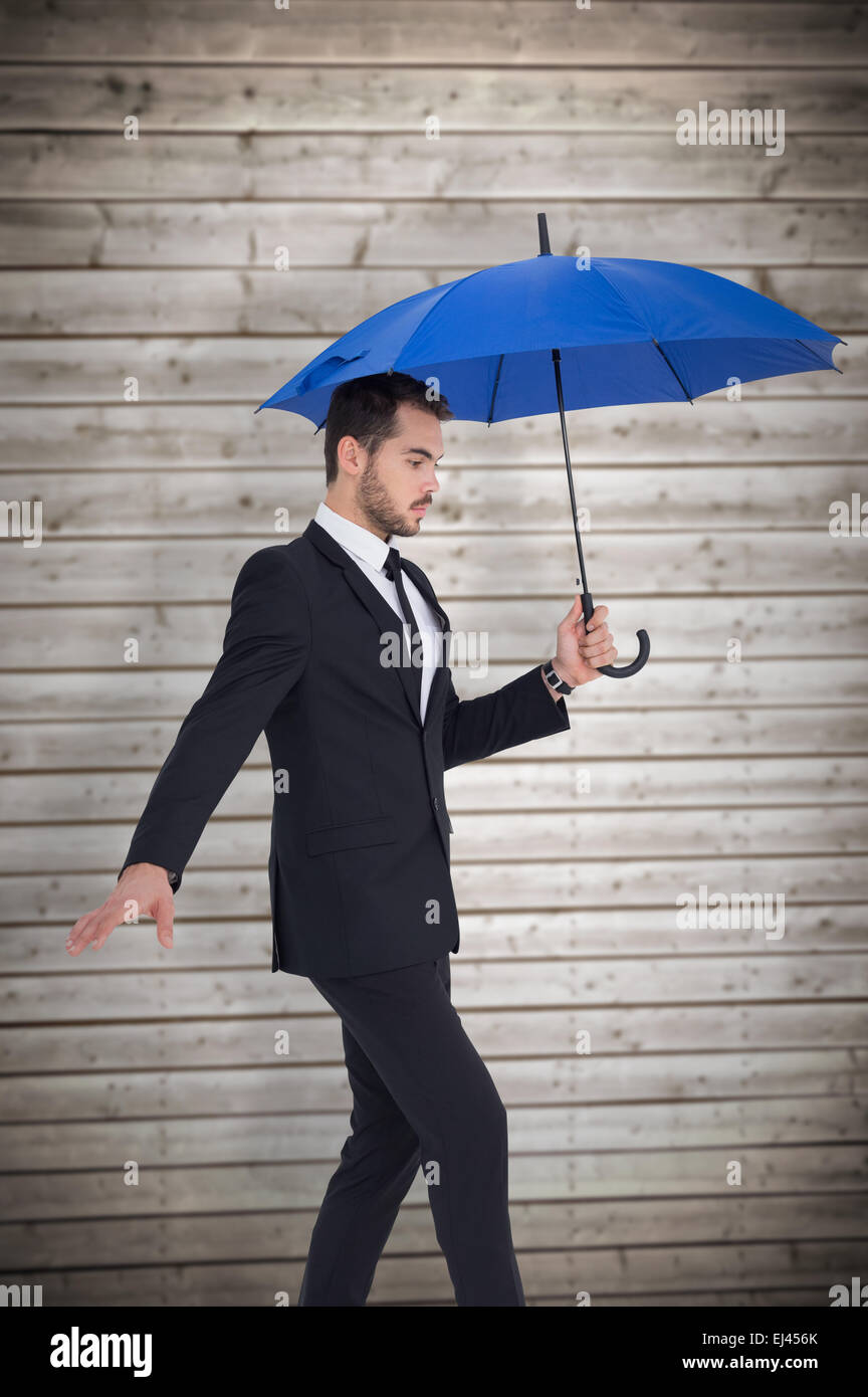 Zusammengesetztes Bild konzentrierte Geschäftsmann Holding Regenschirm beim treten Stockfoto