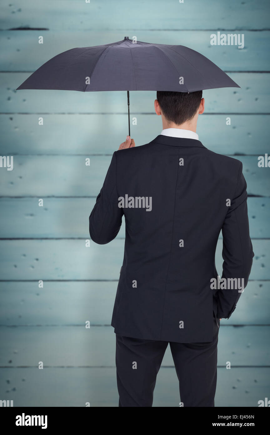 Zusammengesetztes Bild der Rückansicht der Geschäftsmann bergende mit Regenschirm Stockfoto