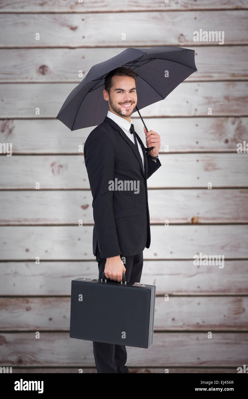 Zusammengesetztes Bild des lächelnden Geschäftsmann unter Dach mit einer Aktentasche Stockfoto