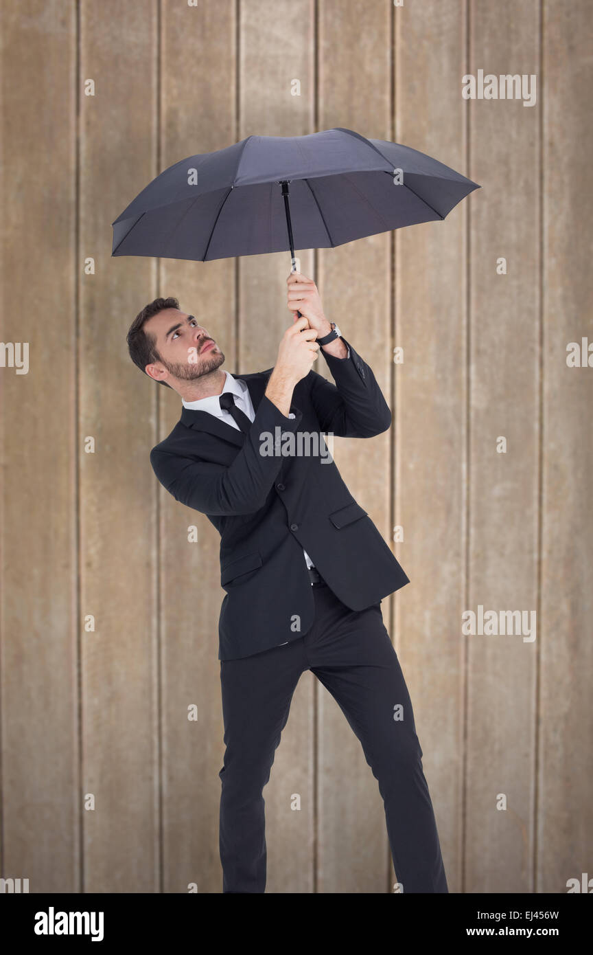 Zusammengesetztes Bild des Kaufmanns stehen unter schwarzen Regenschirm Stockfoto