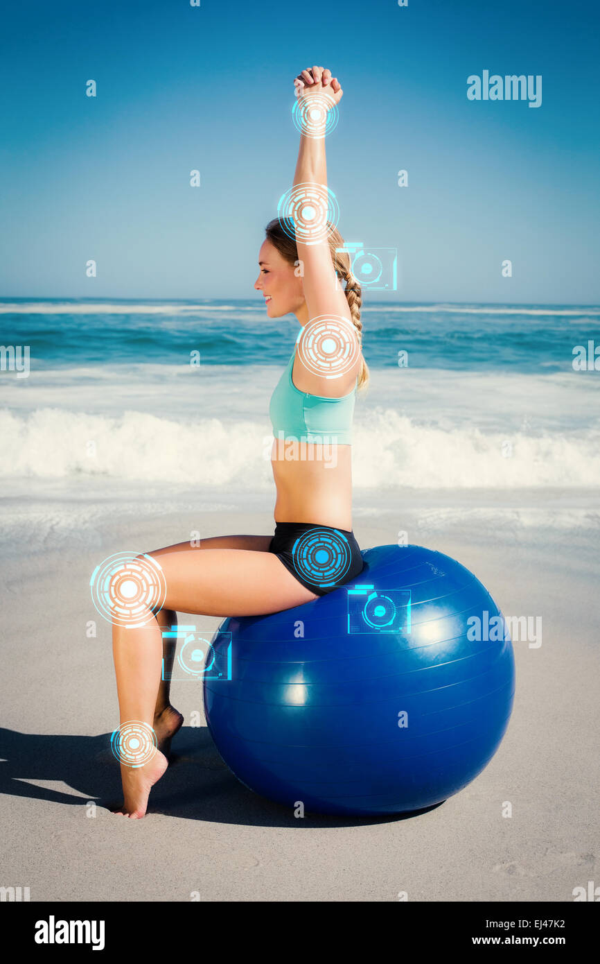 Zusammengesetztes Bild Fit Frau sitzen auf Gymnastikball am Strand Strecken Arme Stockfoto