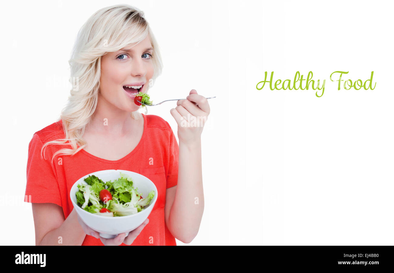 Gesunde Ernährung gegen Gemüsesalat gegessen von einer lächelnden blonder Frau Stockfoto
