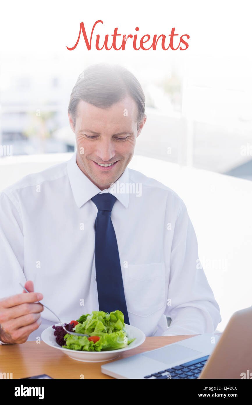 Nährstoffen gegen lächelnden Geschäftsmann Essen einen Salat auf seinem Schreibtisch Stockfoto