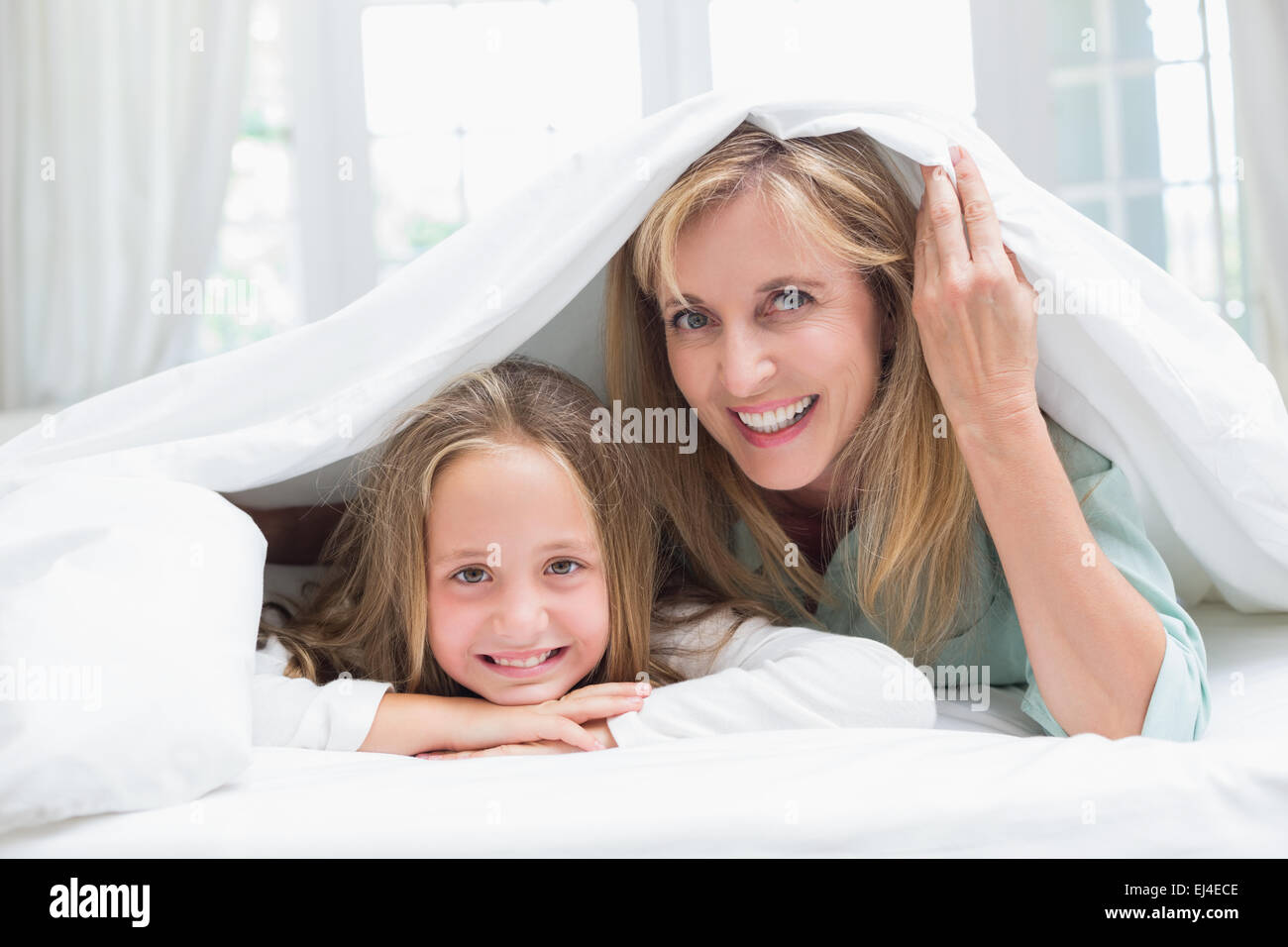 Mutter und Tochter Blick in die Kamera unter der Bettdecke Stockfoto