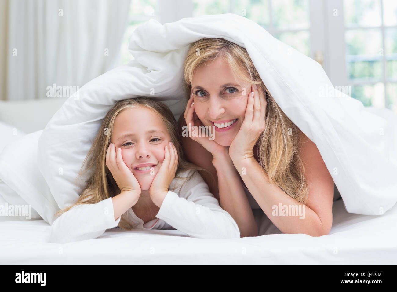 Mutter und Tochter Blick in die Kamera unter der Bettdecke Stockfoto