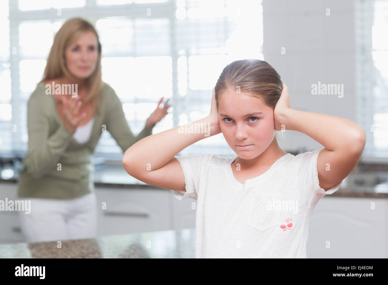 Aufgeregt Mädchen für ihre Ohren während ihre Mutter schreien Stockfoto