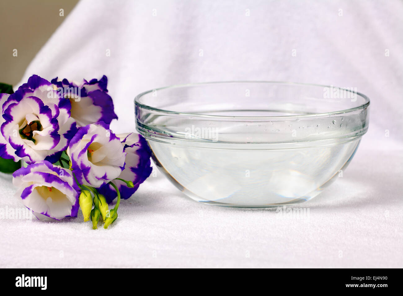 Schüssel mit Wasser auf weißen Schwimmsachen mit Eustoma Blume Stockfoto