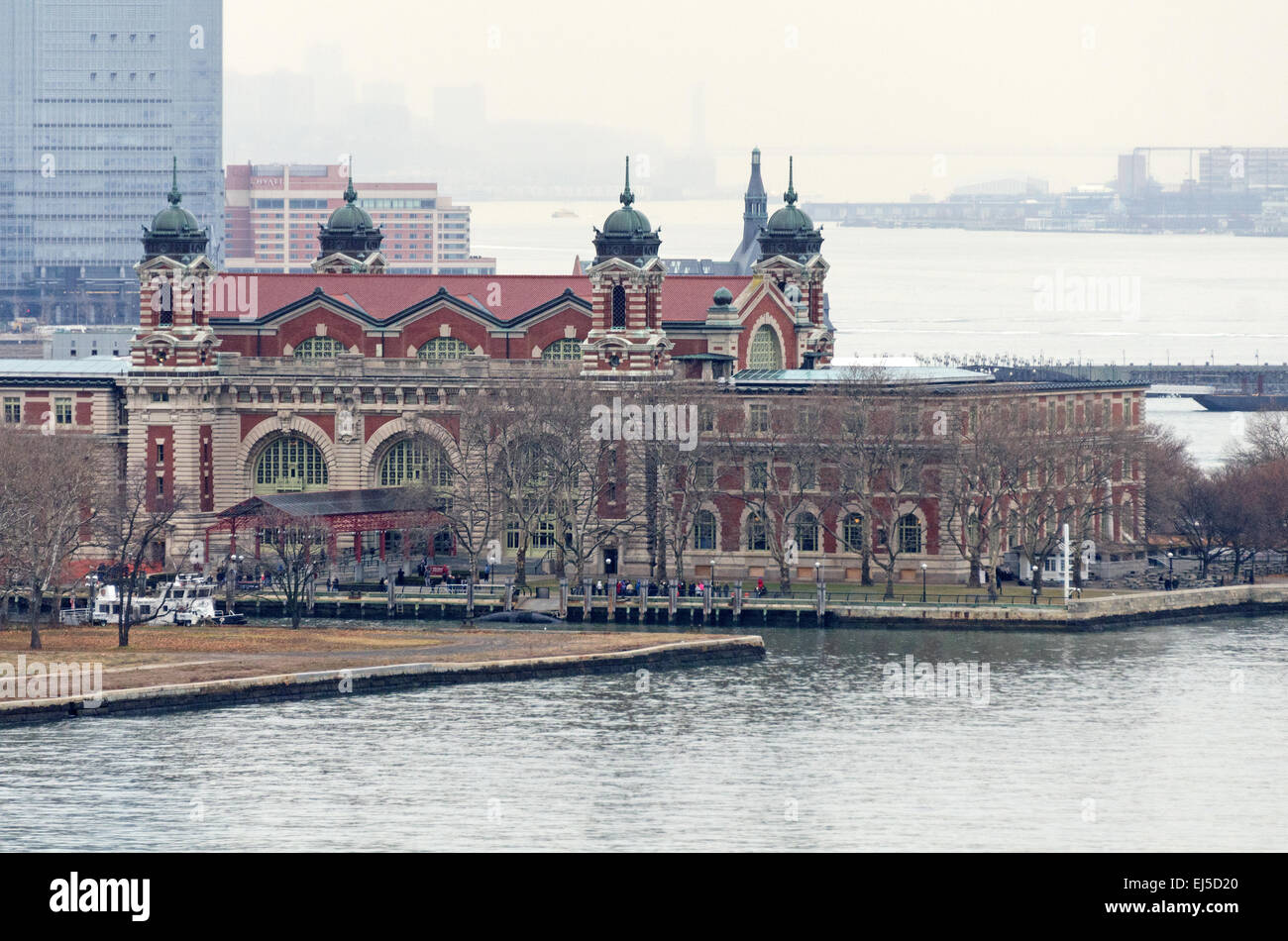 Das Hauptgebäude der Ellis Island Immigration Museum gesehen von der New Yorker Freiheitsstatue an einem regnerischen Nachmittag, New York City. Stockfoto