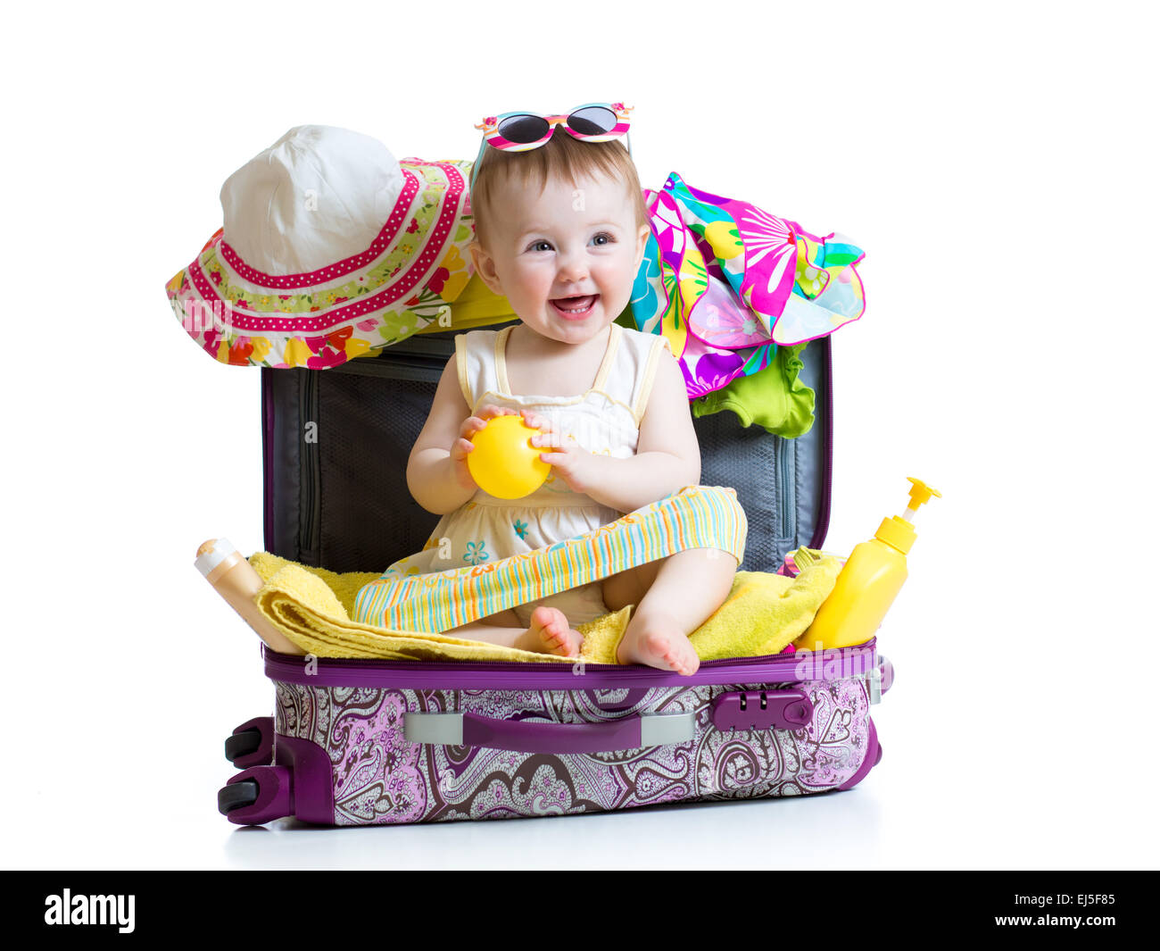 Babymädchen sitzen im Koffer mit Dingen für Urlaubsreisen Stockfoto