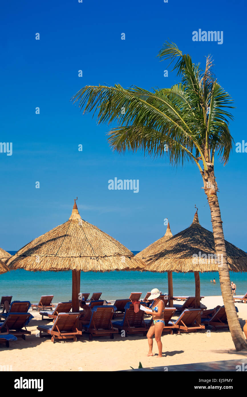 Palme und strohgedeckten Sonnenschirmen und Liegestühlen am Strand von Vinpearl Resort. Insel Phu Quoc, Provinz Kien Giang, Vietnam. Stockfoto