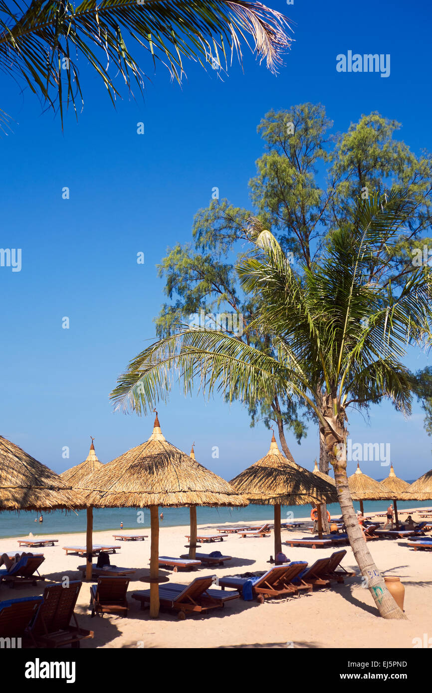 Palme und strohgedeckten Sonnenschirmen und Liegestühlen am Strand von Vinpearl Resort. Insel Phu Quoc, Provinz Kien Giang, Vietnam. Stockfoto