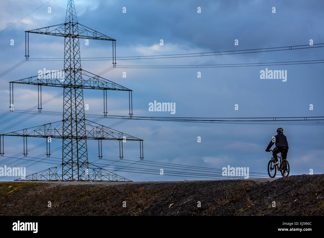 Person auf dem Fahrrad, auf einem Hügel, mit großer Kraft pole, Pylon, hinten Stockfoto