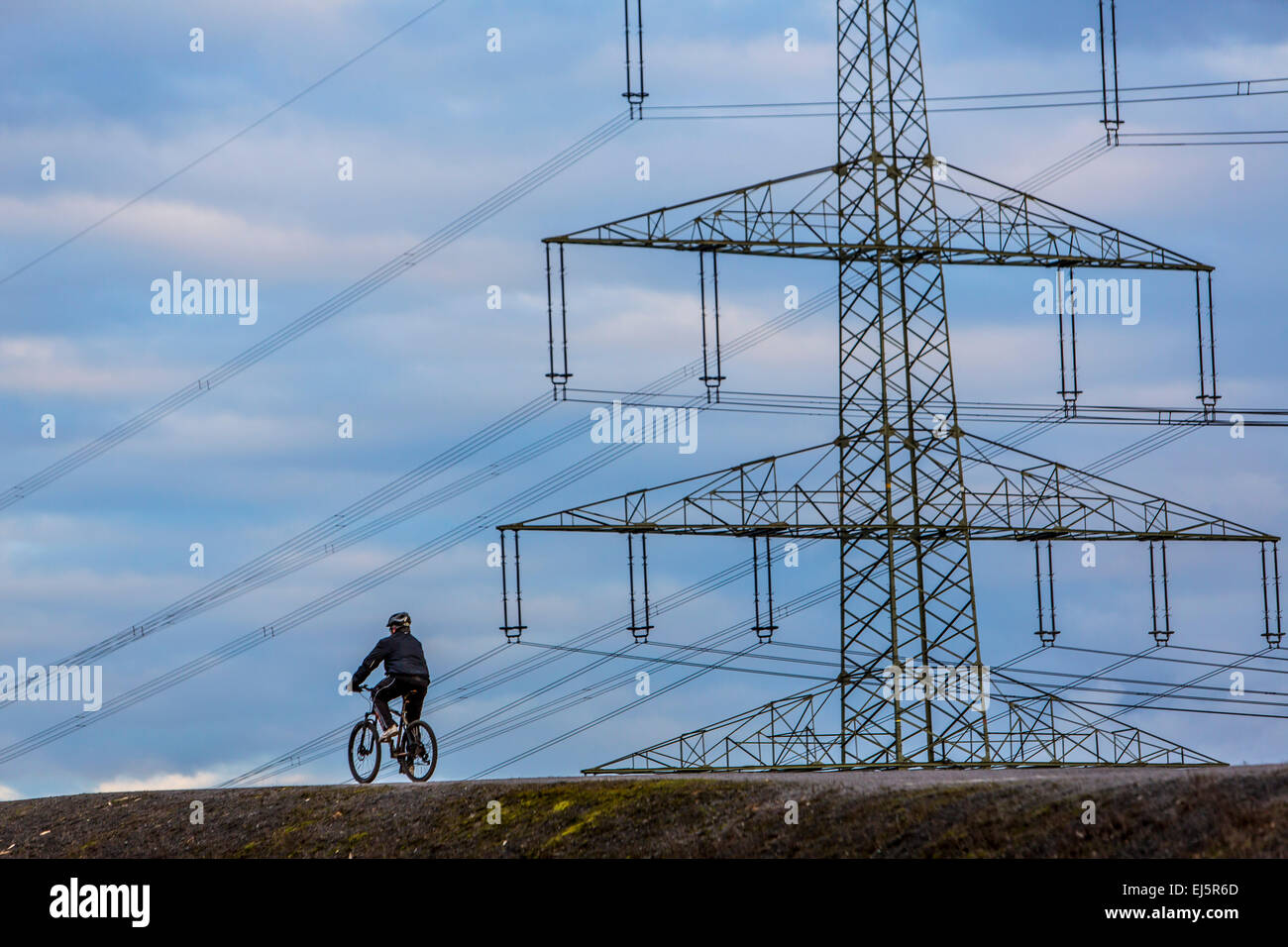 Person auf dem Fahrrad, auf einem Hügel, mit großer Kraft pole, Pylon, hinten Stockfoto