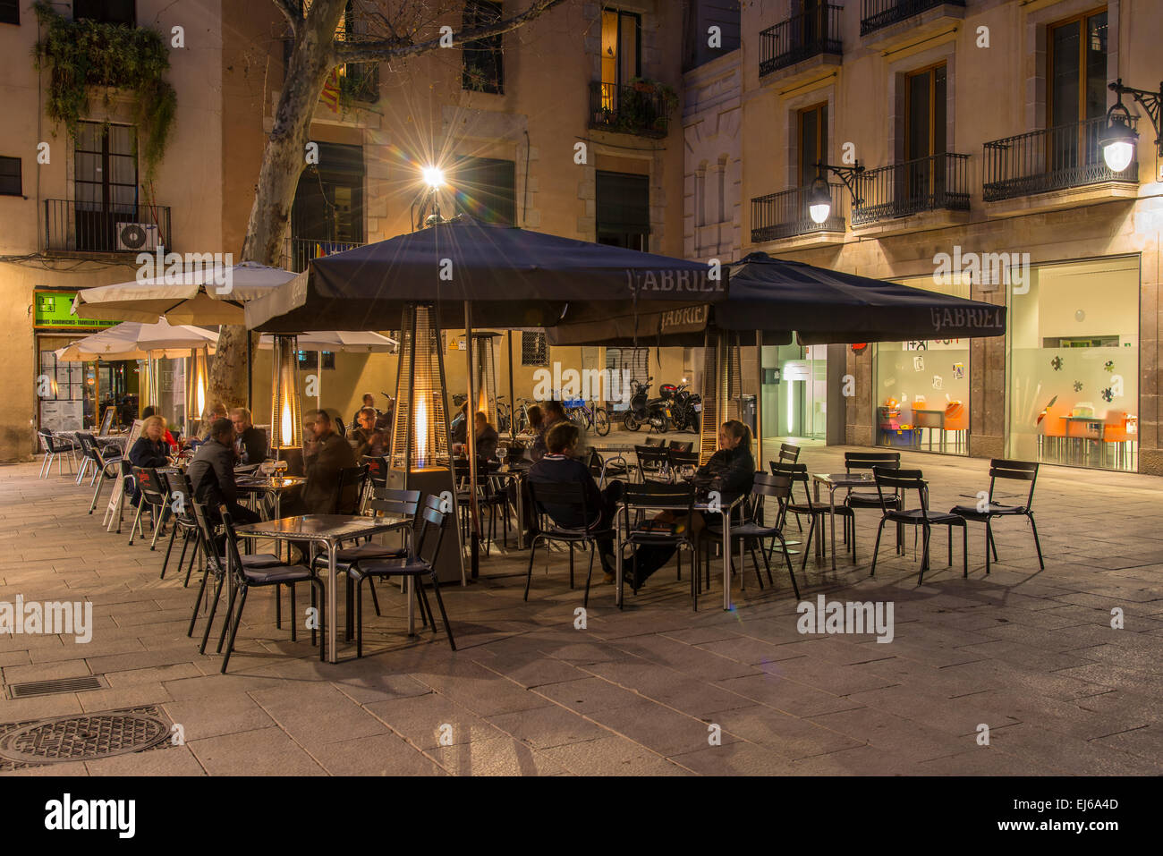 Nachtansicht von einem Straßencafé mit Touristen, die an den Tischen in einem Quadrat von Barrio Gotico, Barcelona, Katalonien, Spanien Stockfoto