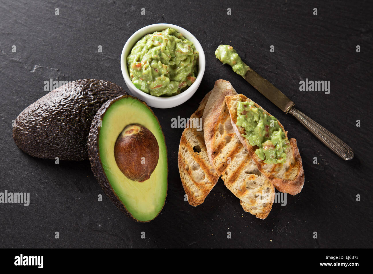 Guacamole mit Brot und Avocado auf Stein Hintergrund Stockfoto