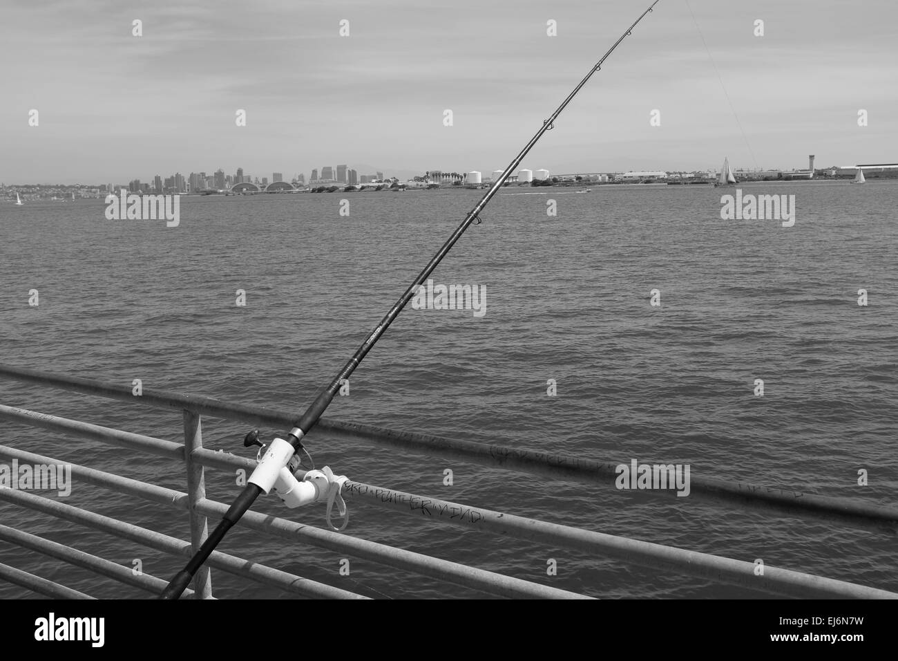 Fischer und Pelikane auf Shelter Island Pier, San Diego Bay, Angelrute in Halter auf der Schiene Stockfoto