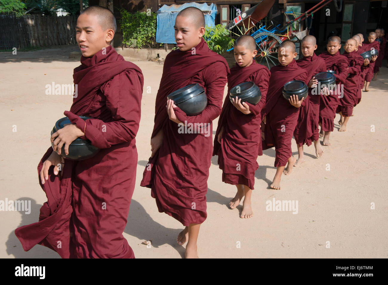 Mönchen Almosen Wok halten, in der Schlange für Essen im Dorf, Bagan, Mandalay Region, Myanmar Stockfoto