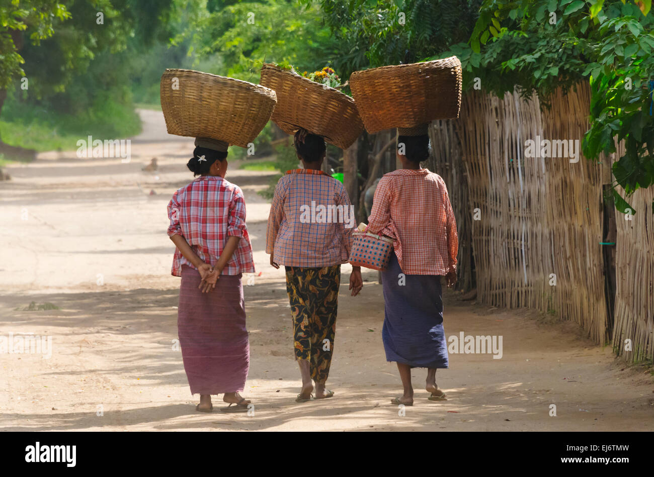 Frauen, die Körbe auf dem Kopf in das Dorf, Bagan, Mandalay Region, Myanmar Stockfoto