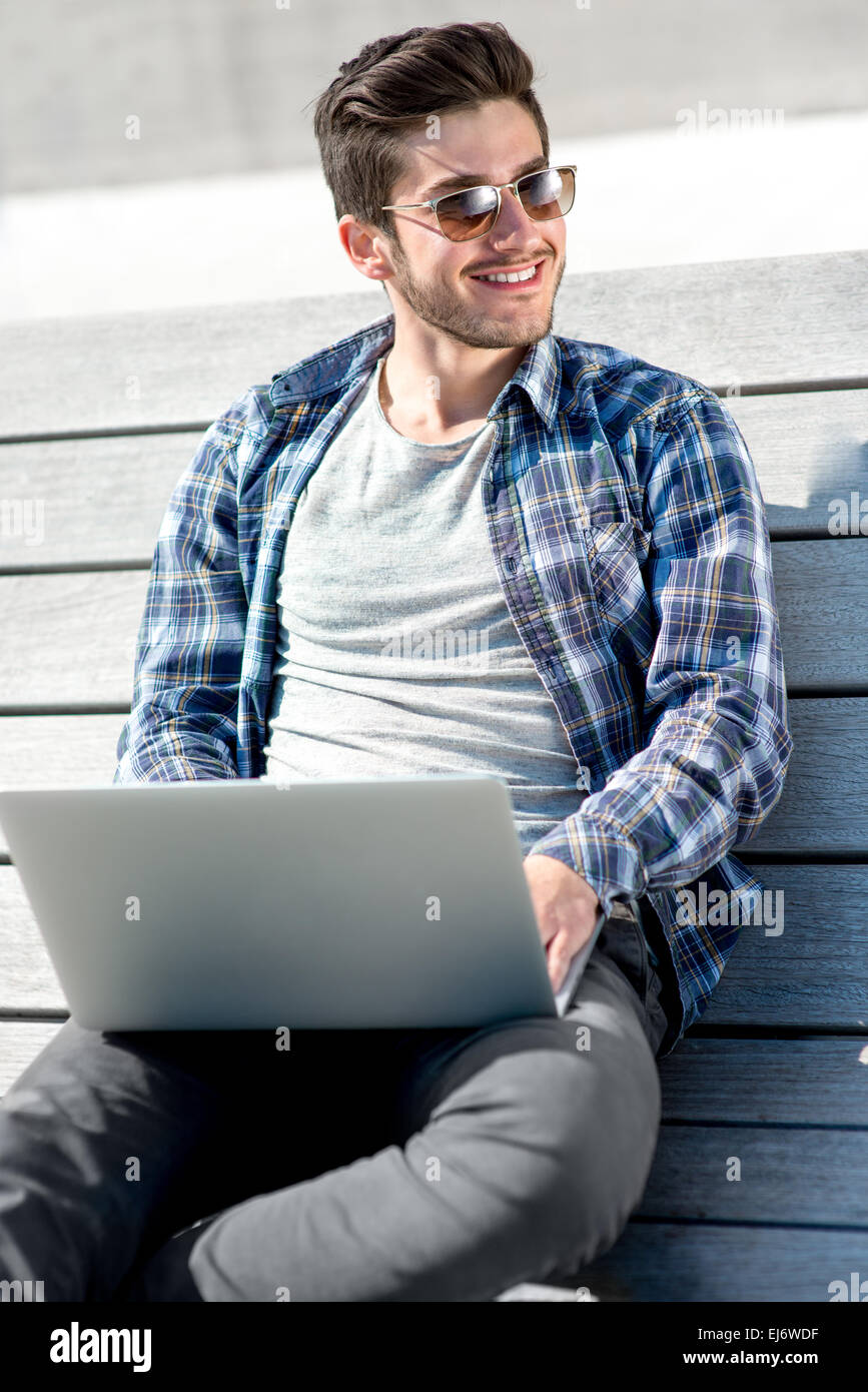 Porträt des jungen Mann mit Laptop auf der Bank Stockfoto
