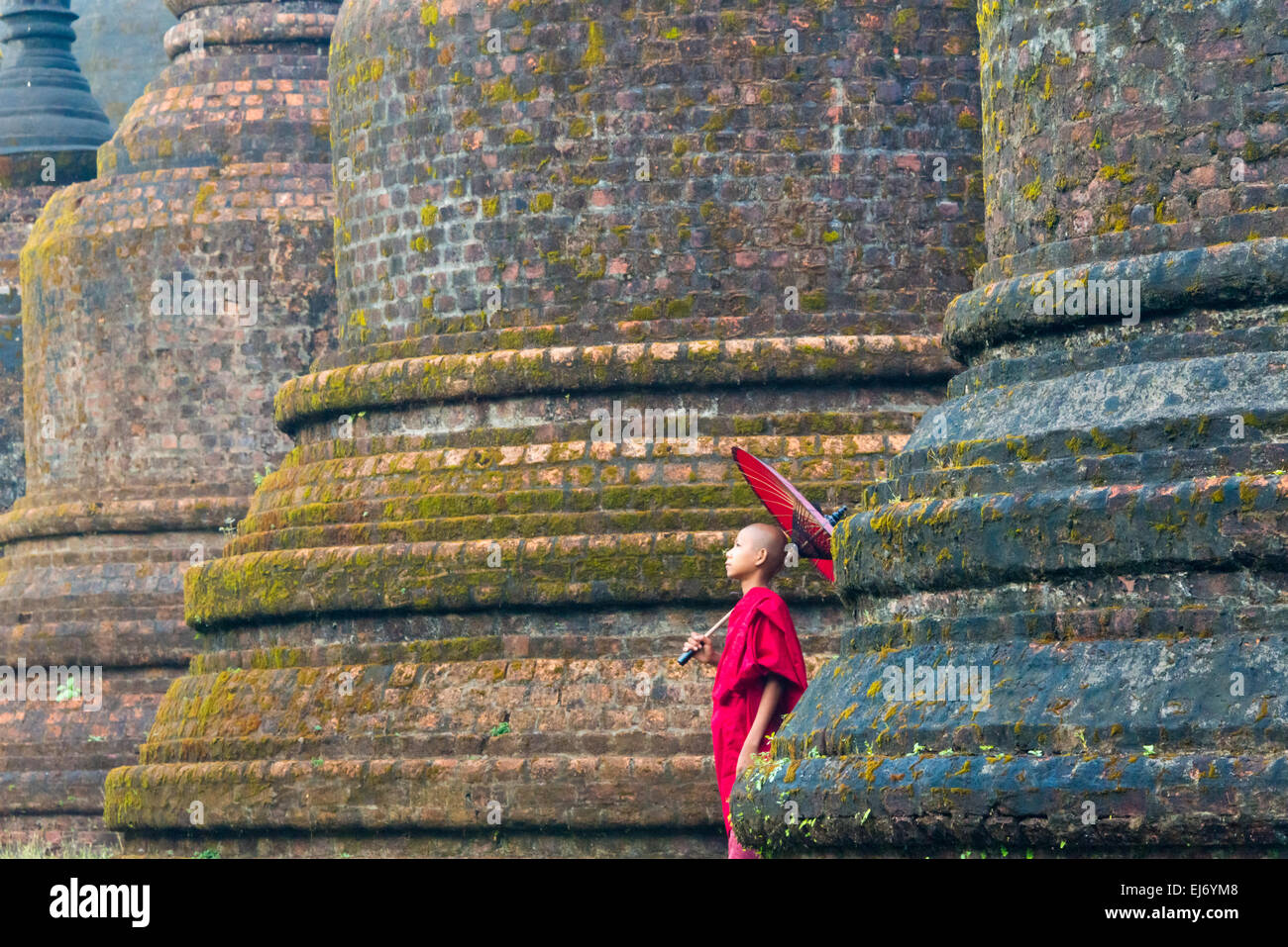 Mönch mit roten Regenschirm mit Andaw-Thein Tempel, Mrauk U, Rakhine State in Myanmar Stockfoto