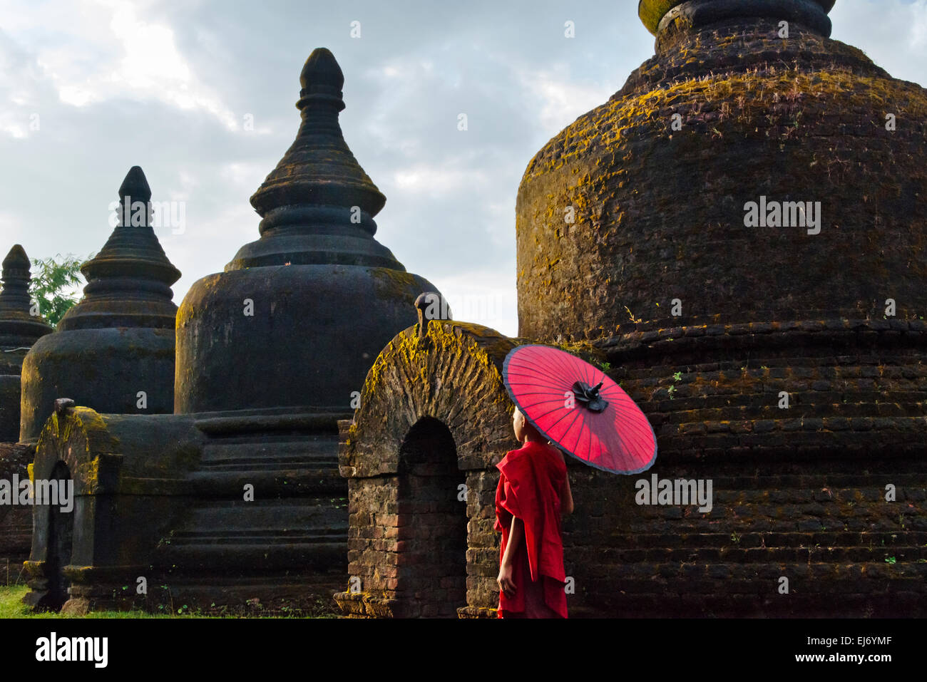 Mönch mit roten Regenschirm mit Andaw-Thein Tempel, Mrauk U, Rakhine State in Myanmar Stockfoto