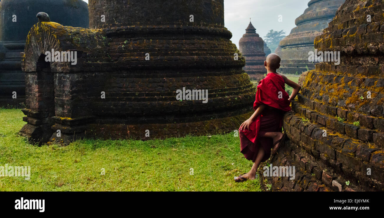 Mönch mit roten Regenschirm mit Andaw-Thein Tempel, Mrauk U, Rakhine State in Myanmar Stockfoto