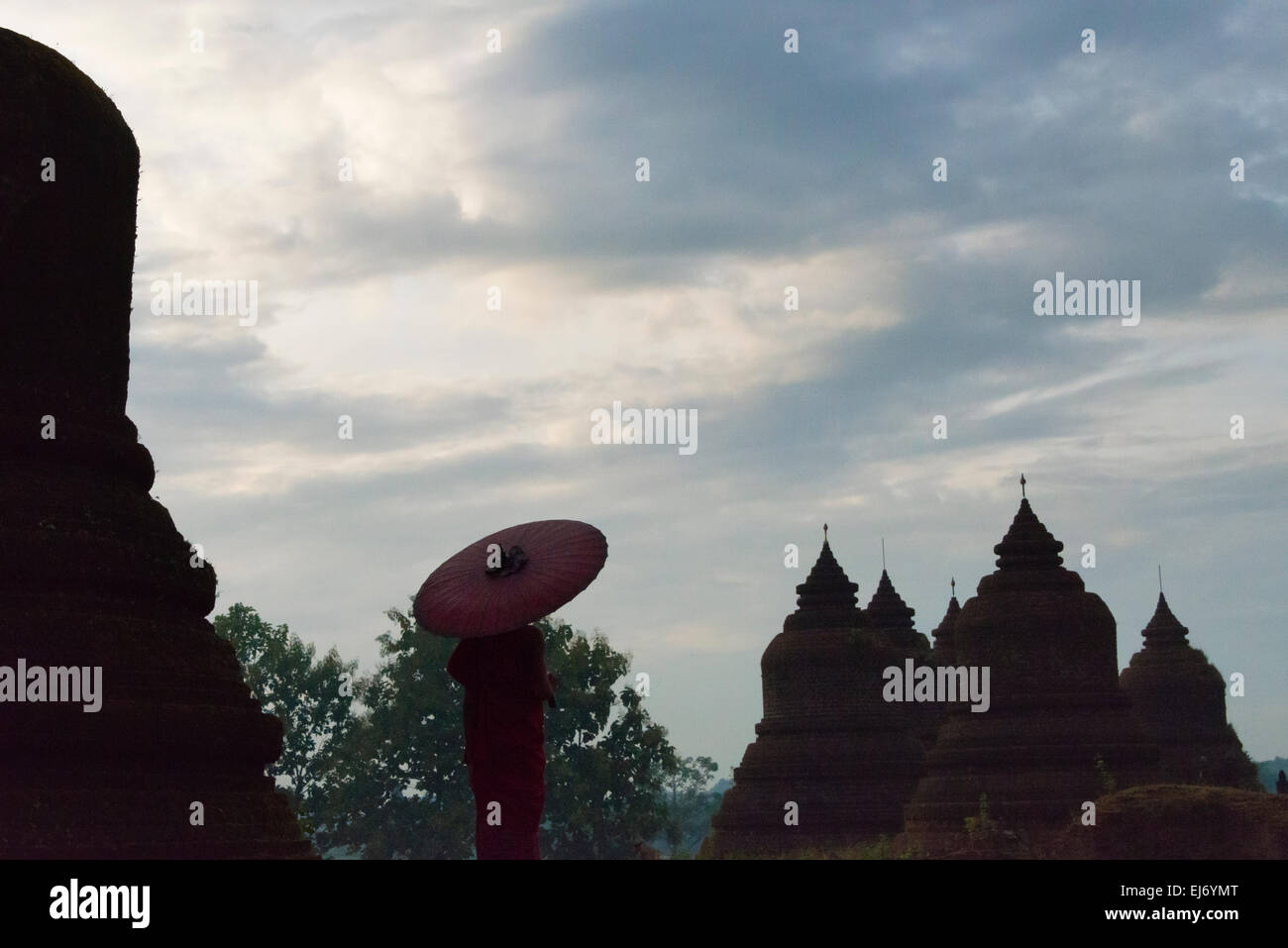 Mönch mit roten Regenschirm mit Andaw-Thein Tempel, Mrauk U, Rakhine State in Myanmar Stockfoto